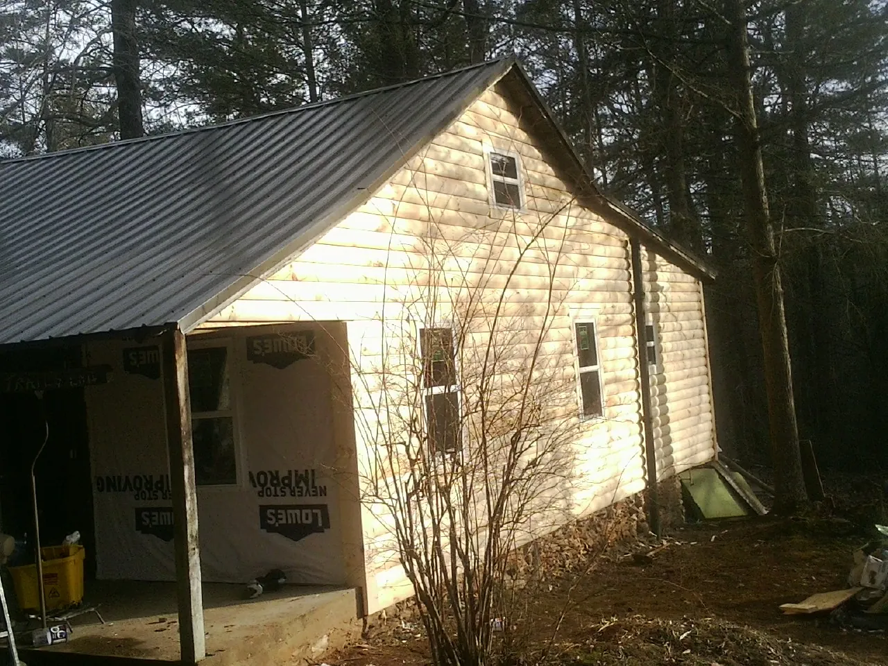 Log siding gable end under a dark metal roof edge in Waverly